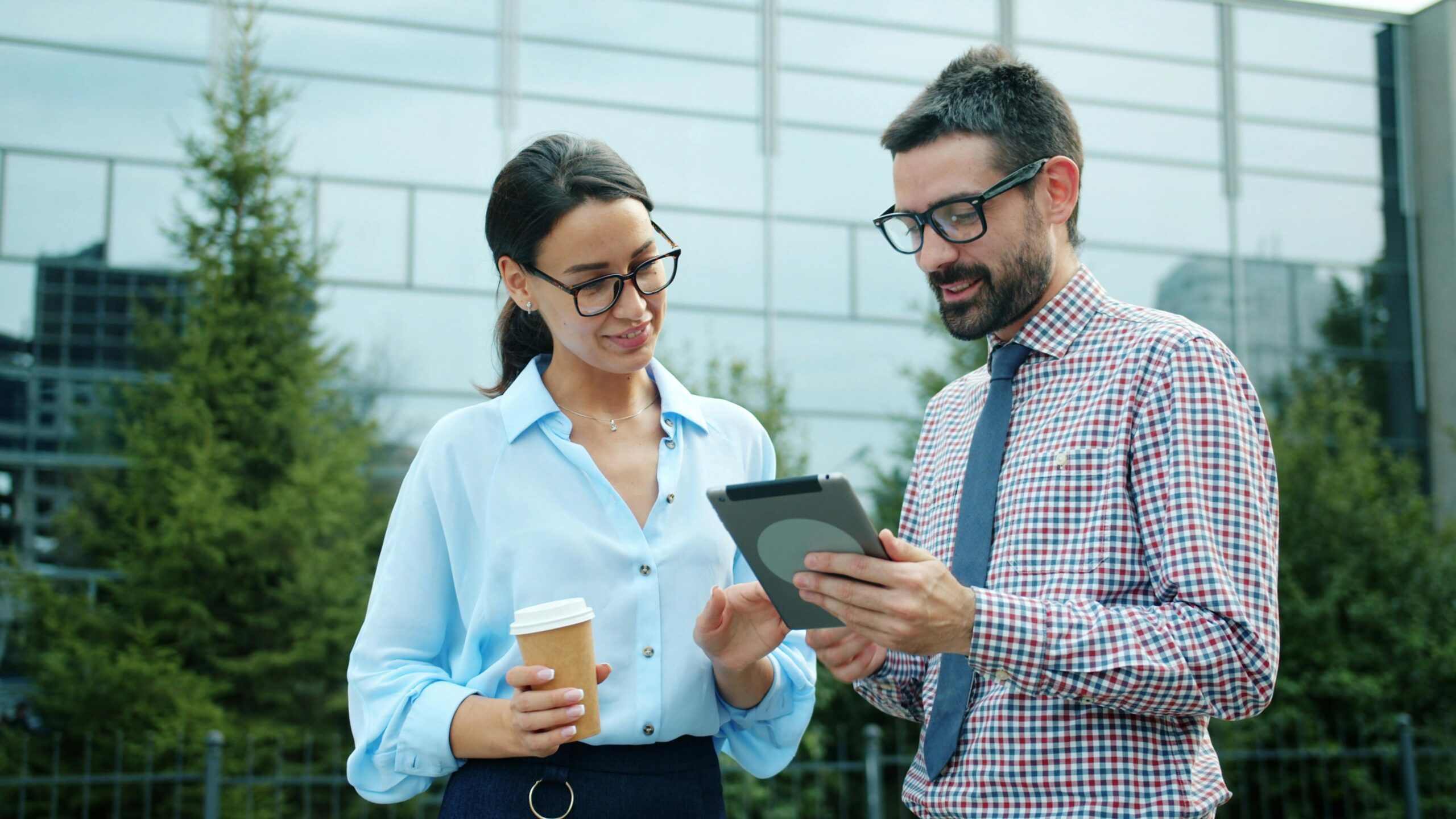 Two professionals discussing work on a tablet outdoors.